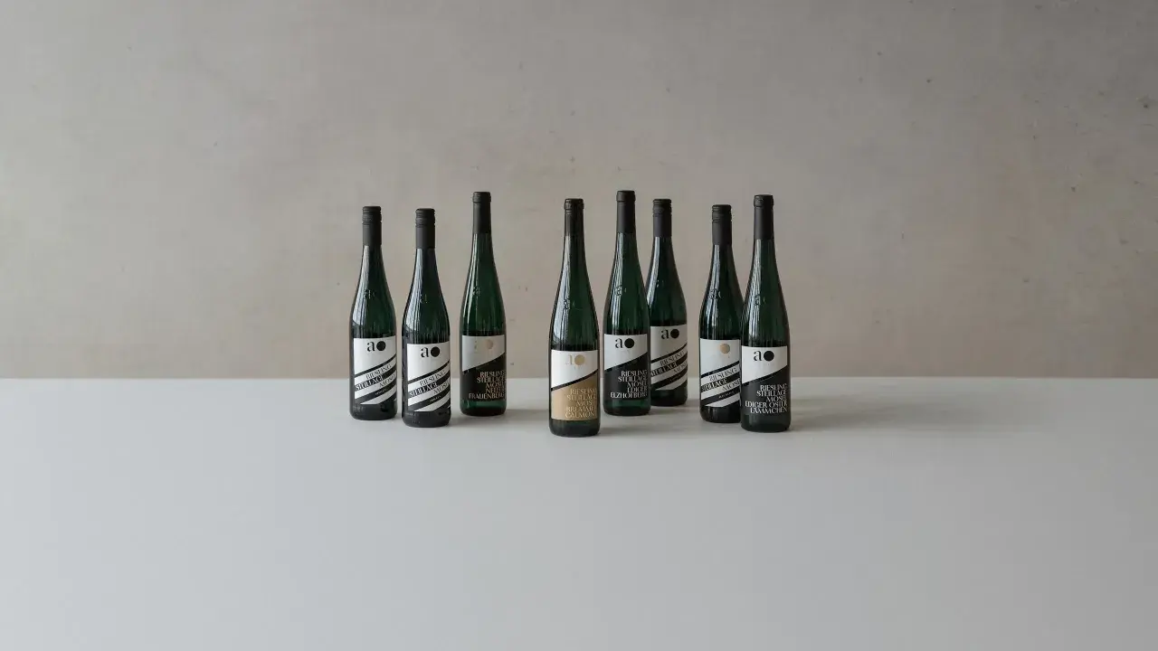 Neun Flaschen Wein der Andreas Oster Weinkellerei stehen nebeneinander.
