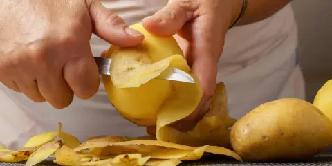 Hände schälen Kartoffeln für die Zubereitung. Bald sind die Kartoffeln gar und bereit zum Genuss.