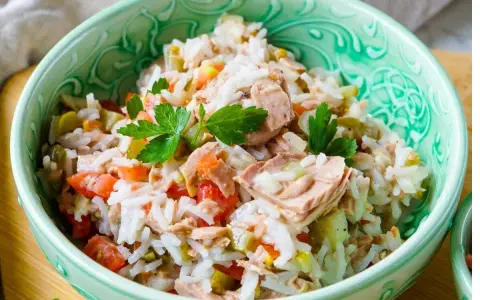 Schüssel mit Reissalat mit Thunfisch, Tomaten, Gurken und Petersilie. Ein leckeres und einfaches Gericht.