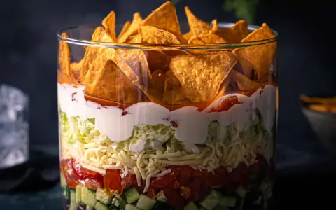 Schichtsalat im Glas: knackige Gurken, Tomaten, Käse, Salat, cremige Soße und Tortilla-Chips. Ein köstlicher nacho salat.