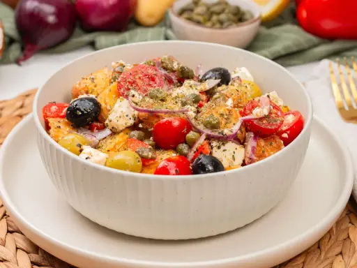 Schüssel mit einem frischen griechischen Kartoffelsalat, garniert mit Oliven, Tomaten, Kapern und Feta.