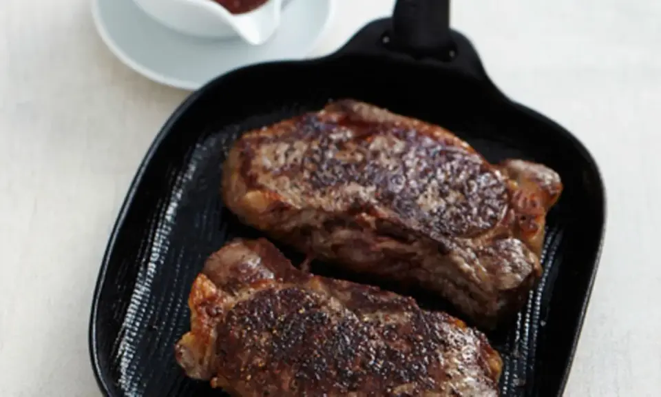 Zwei saftige Rumpsteaks braten in einer Grillpfanne, perfekt gewürzt und bereit zum Genuss.
