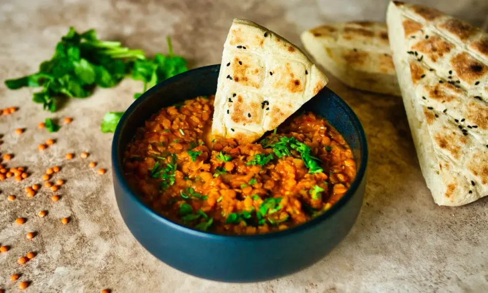 Herzhafte Linsenrezepte: Ein dampfender Linseneintopf mit frischer Petersilie und Fladenbrot.
