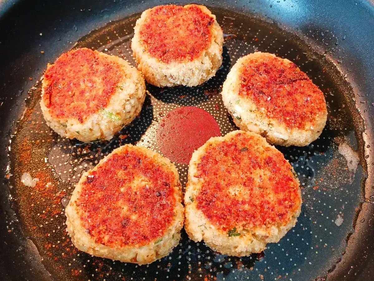 F&uuml;nf goldbraune, vegetarische Frikadellen braten in einer Pfanne. Sie duften herrlich nach Gew&uuml;rzen und sind bereit zum Genie&szlig;en.