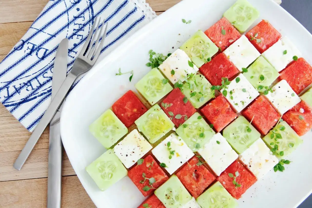 Erfrischender Melonen Feta Salat, kunstvoll arrangiert in W&uuml;rfeln mit Gurke und frischen Kr&auml;utern.