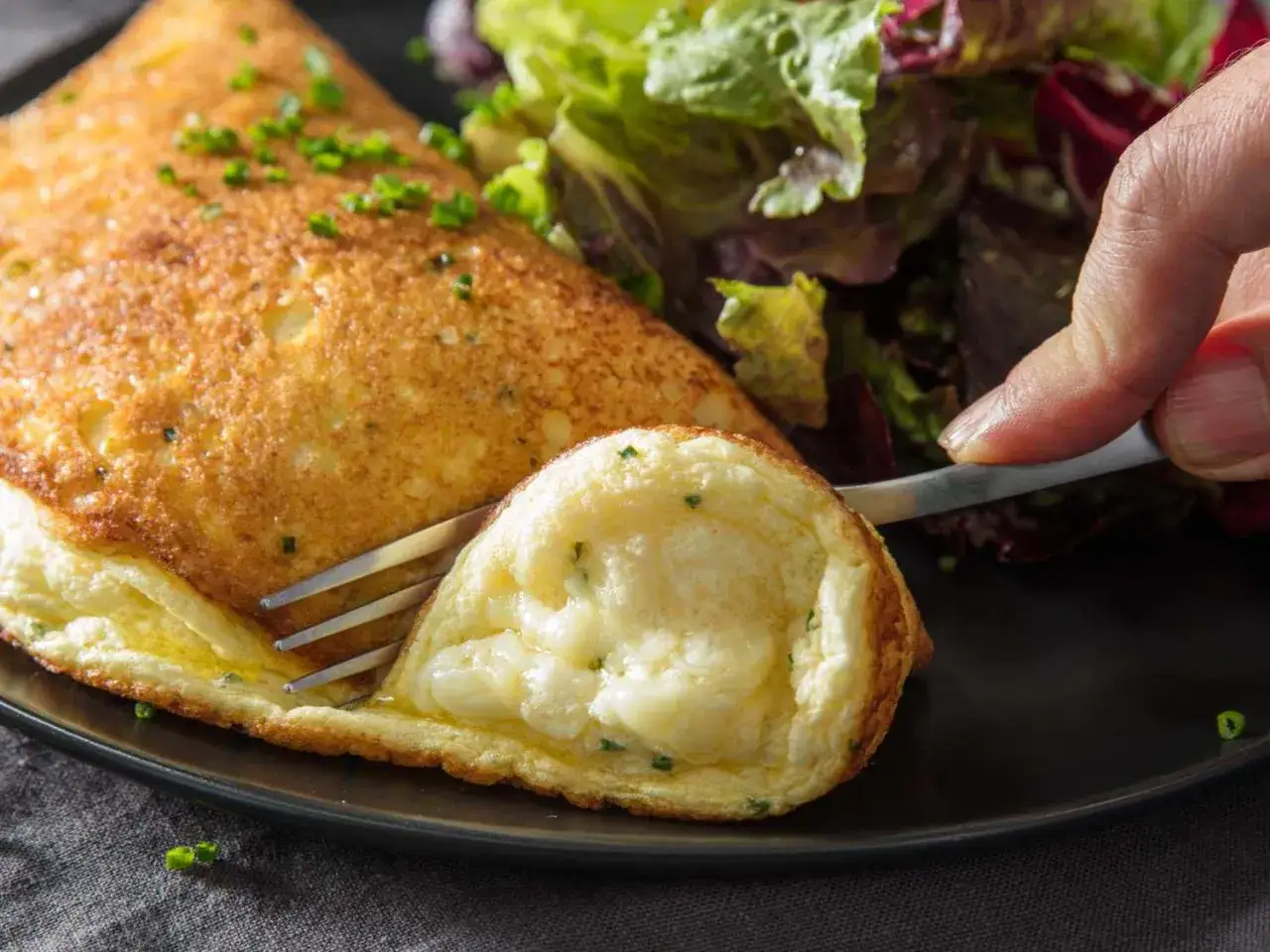 Ein fluffiges Omelett mit K&auml;sef&uuml;llung, perfekt f&uuml;r ein schnelles Omelett Rezept. Daneben ein bunter Salat.