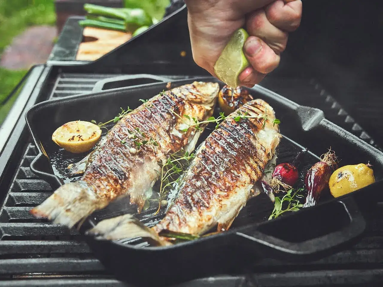 Zwei ganze Forellen werden auf einem Grill zubereitet, mit Zitrone und Kr&auml;utern verfeinert. Das Grillen der Forelle ist ein Genuss.