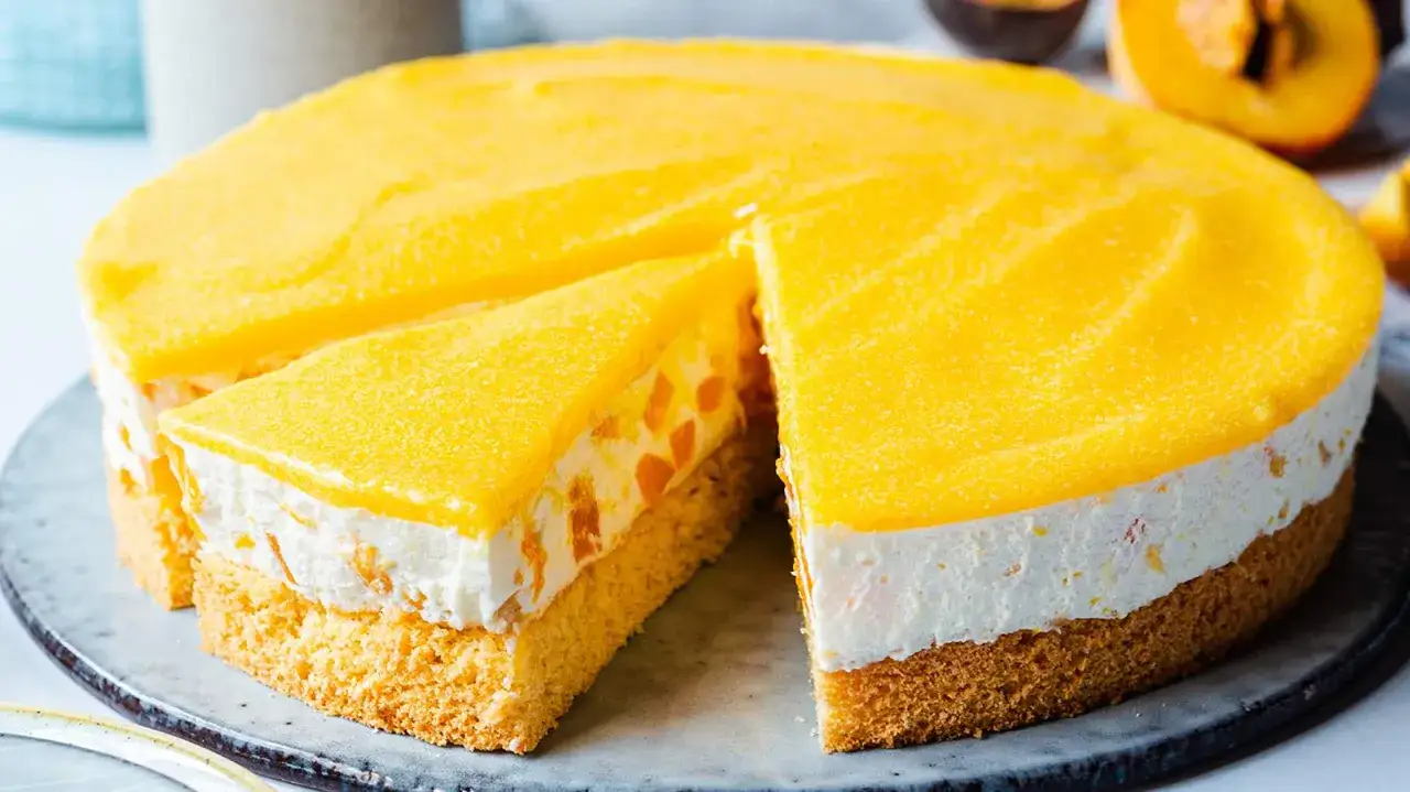 Eine leuchtend gelbe Solero Torte mit saftigen Fruchtst&uuml;ckchen und einer cremigen F&uuml;llung auf einem lockeren Biskuitboden.