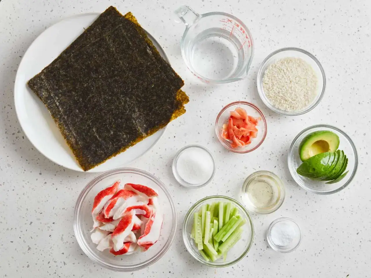Zutaten für Sushi selbst machen: Nori-Blätter, Reis, Avocado, Gurke, Surimi, eingelegter Ingwer, Reisessig, Zucker und Salz.