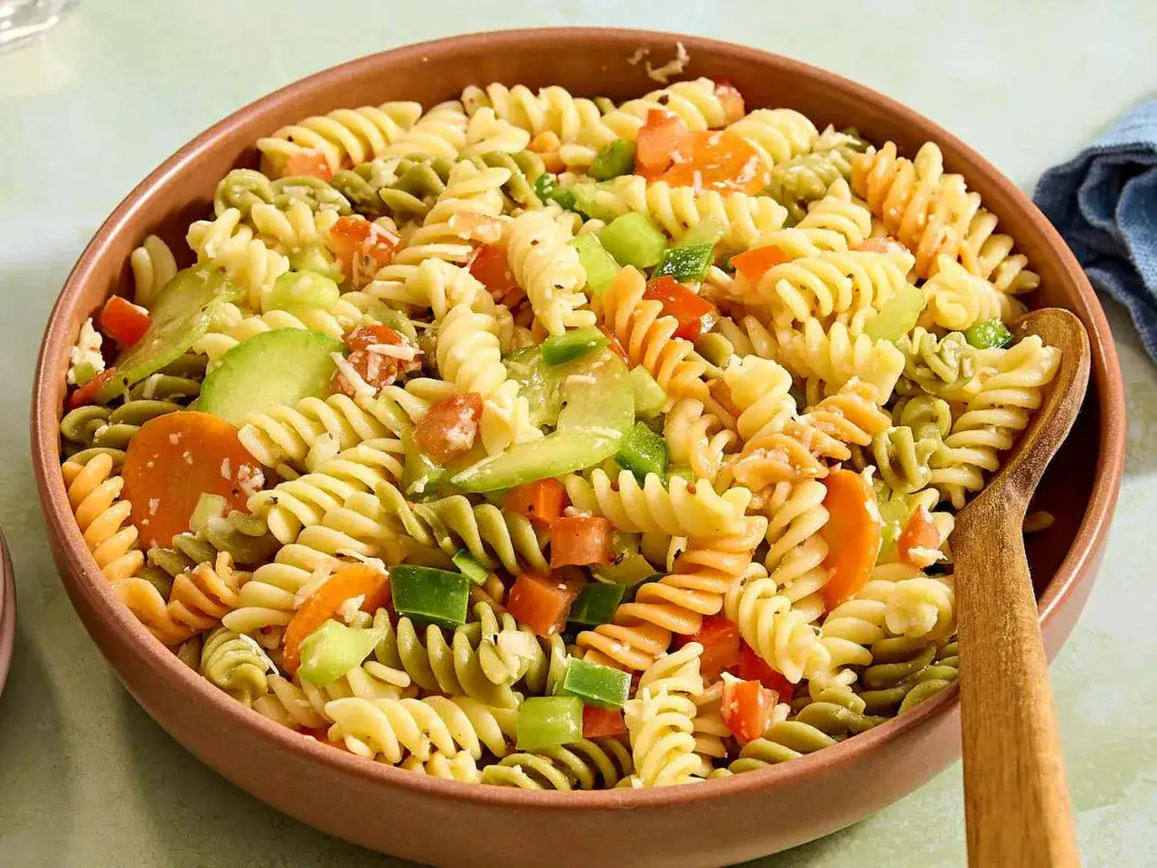 Bunter Nudelsalat ohne Mayonnaise mit Spiralnudeln, Karotten, Paprika und Gurke in einer Sch&uuml;ssel.