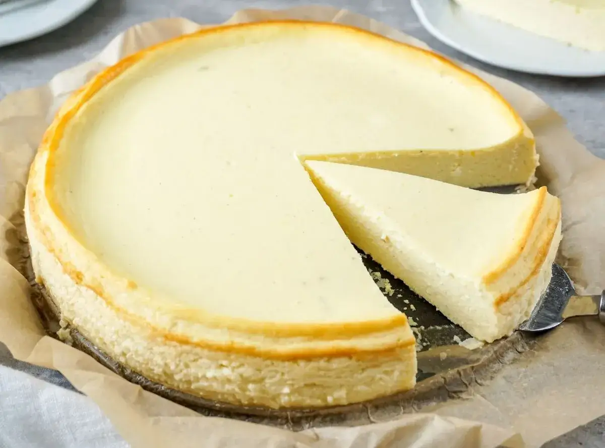 Ein cremiger Quarkkuchen ohne Boden, mit einem St&uuml;ck auf einem Tortenheber.