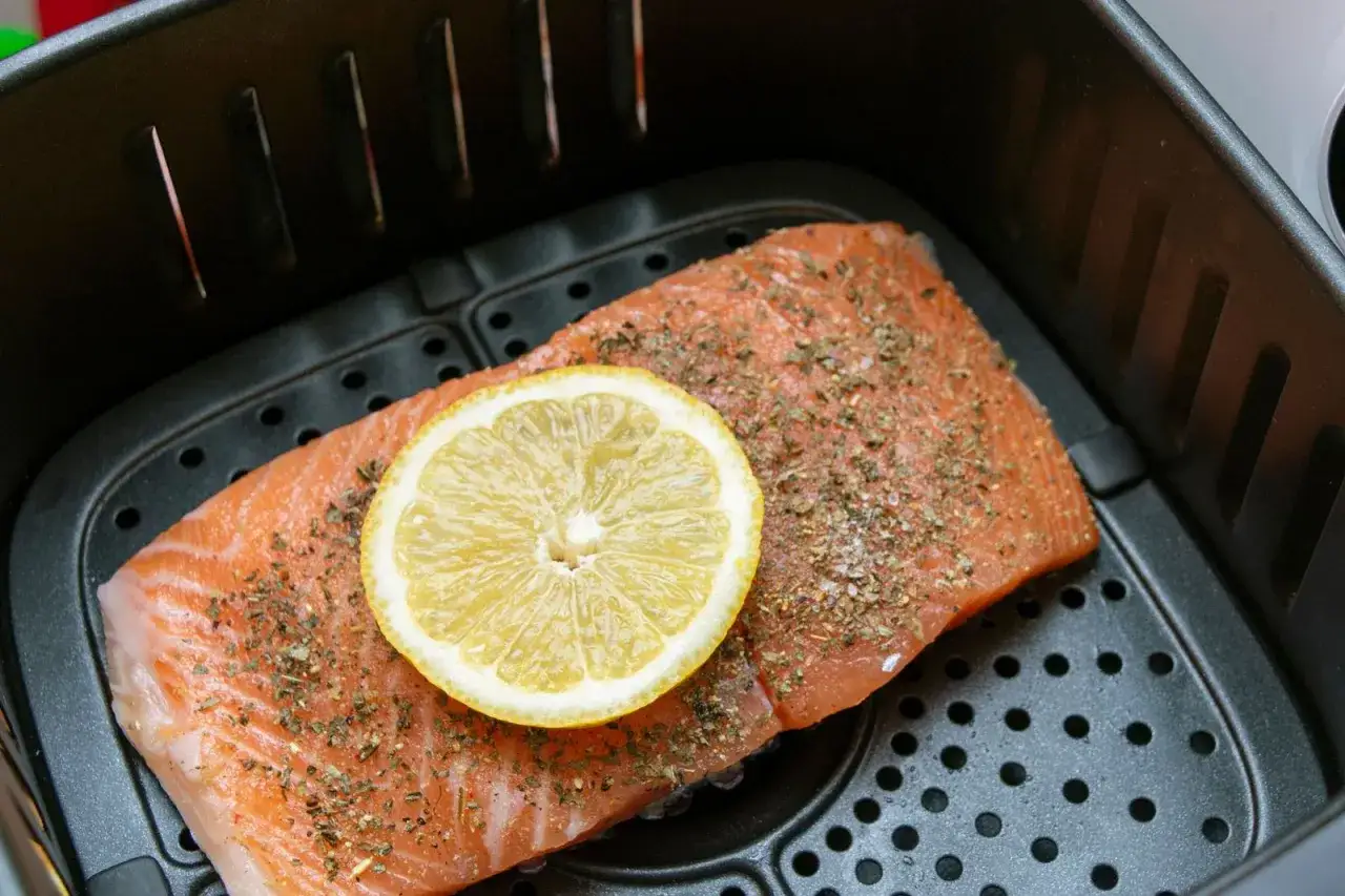 TK Lachs im Airfryer, gew&uuml;rzt und mit Zitronenscheibe belegt, bereit zur Zubereitung.