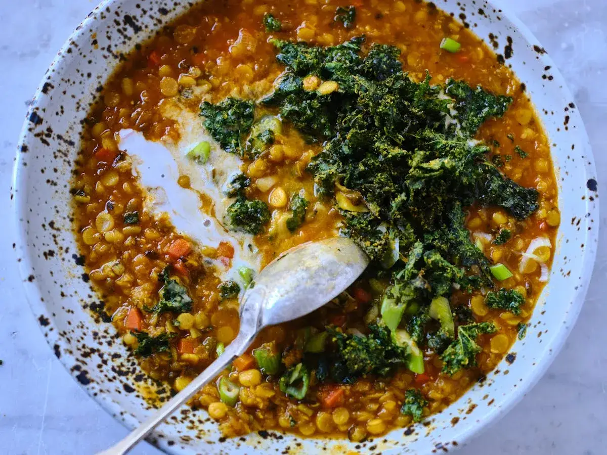 Herzhafte rote Linsensuppe mit Kokosmilch, garniert mit Gr&uuml;nkohl und Fr&uuml;hlingszwiebeln. Eine cremige, w&auml;rmende Mahlzeit.