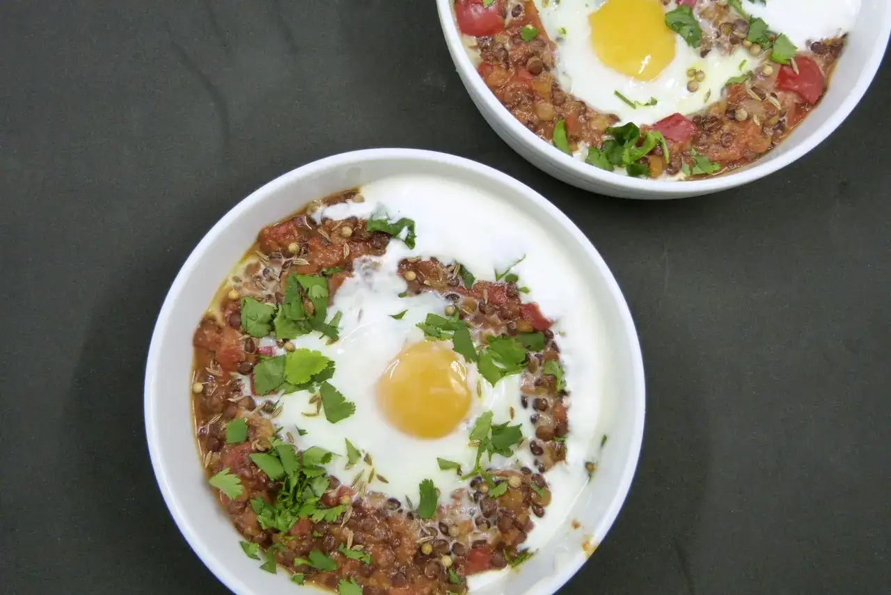 Zwei Schalen mit Linsen-Eintopf, garniert mit Koriander und einem Spiegelei. Ein leckeres Gericht, das zeigt, wie vielseitig Linsen Rezepte sein k&ouml;nnen.